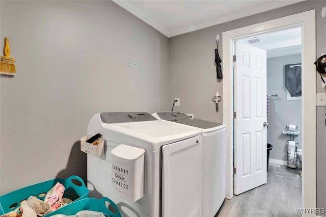 laundry room with washer and dryer, ornamental molding, and light wood-type flooring