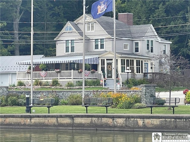 view of front of home with a water view, a porch, and a front lawn