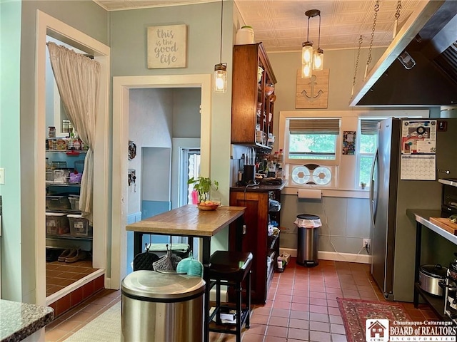 kitchen featuring stainless steel refrigerator, dark tile patterned floors, and pendant lighting