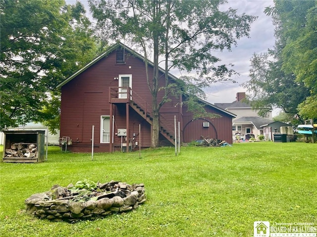 back of property featuring a lawn and an outdoor fire pit