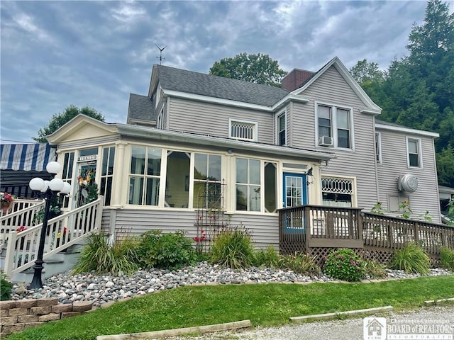 rear view of property with cooling unit, a wooden deck, and a sunroom