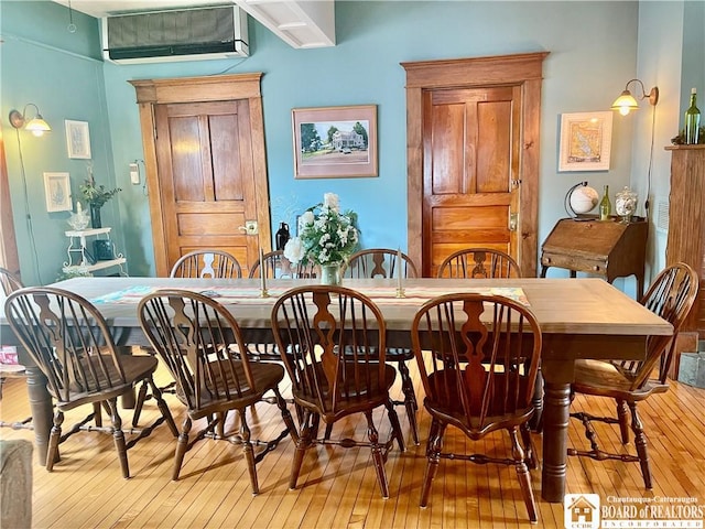 dining space featuring a wall mounted air conditioner and light hardwood / wood-style floors