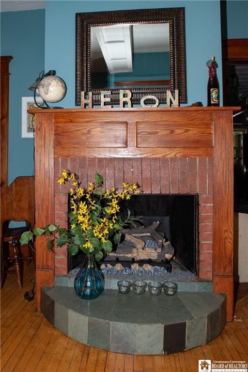 interior details with wood-type flooring and a brick fireplace