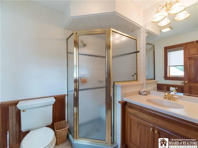 bathroom with a shower with shower door, toilet, a notable chandelier, and vanity