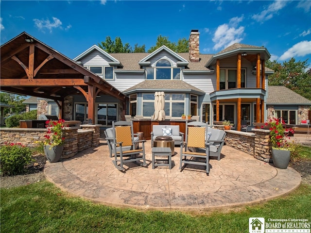 back of house with outdoor lounge area, an outdoor kitchen, and a patio