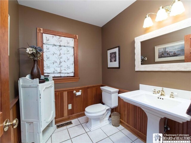 bathroom featuring toilet, wooden walls, and tile patterned flooring