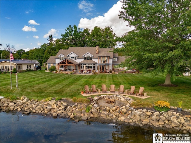 rear view of property with a water view and a lawn