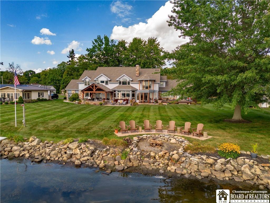 rear view of property featuring a patio area, a chimney, a fire pit, and a yard