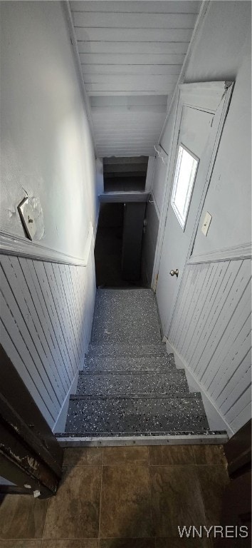 stairway with wooden walls and tile patterned flooring