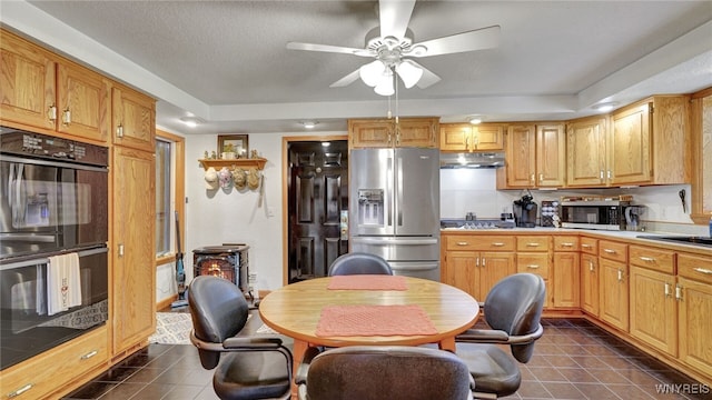 kitchen with dark tile patterned flooring, a textured ceiling, stainless steel appliances, ceiling fan, and a raised ceiling