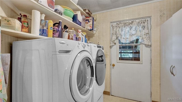 clothes washing area with tile walls and washer and dryer