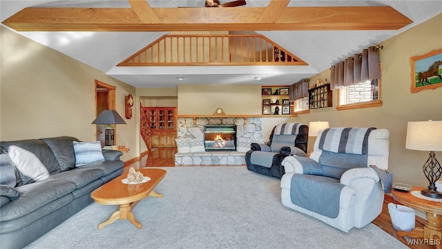 living room featuring lofted ceiling with beams, wood-type flooring, and a stone fireplace