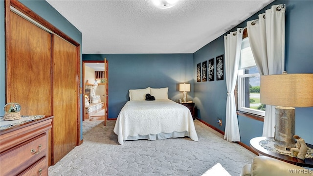 bedroom featuring light carpet, a textured ceiling, and a closet