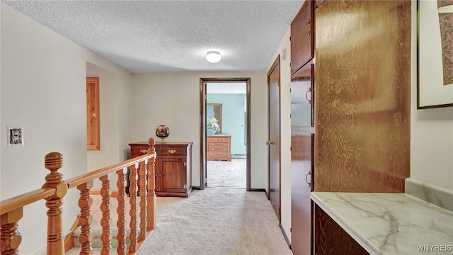 hall with a textured ceiling and light colored carpet