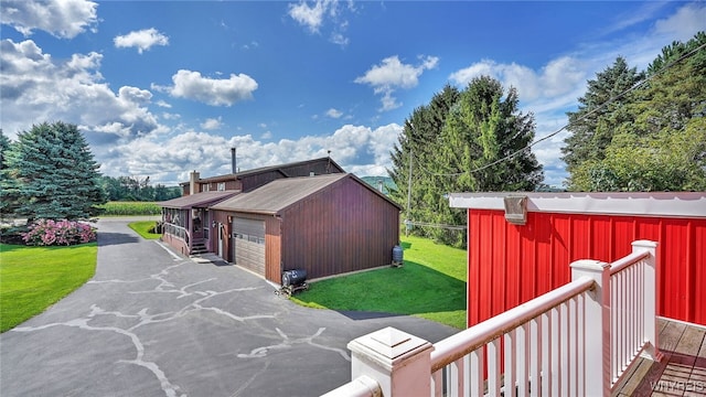 view of side of home featuring a garage, a yard, and an outbuilding