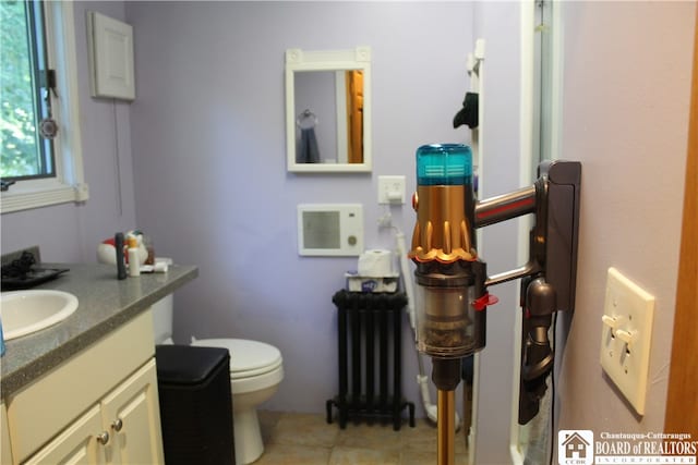 bathroom with vanity, toilet, radiator, and tile patterned flooring