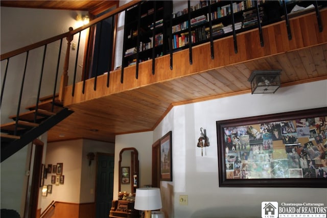 interior space featuring ornamental molding, wood ceiling, and wooden walls