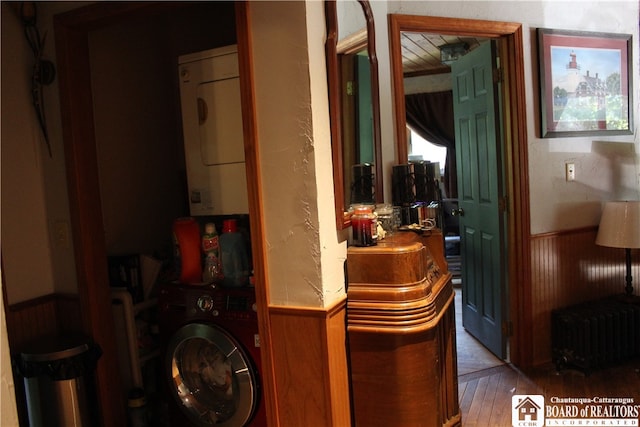 interior space with radiator, stacked washer / drying machine, and hardwood / wood-style flooring