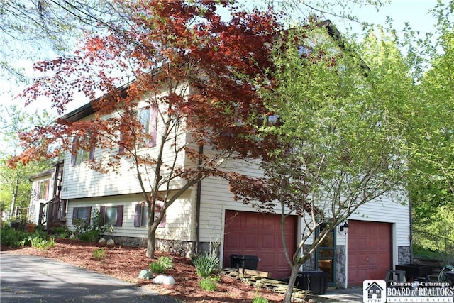222 Seymour St, Pomfret, NY 14063 - view of front of house featuring an attached garage, stone siding, and driveway