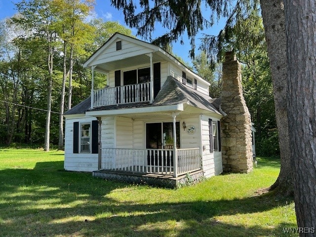 view of front facade featuring covered porch, a balcony, and a front yard