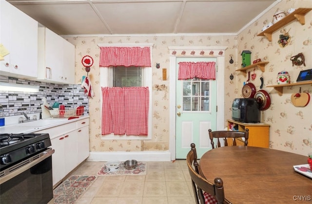 kitchen featuring backsplash, stainless steel range with gas stovetop, white cabinetry, sink, and light tile patterned flooring