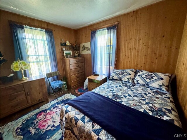 bedroom featuring multiple windows and wooden walls