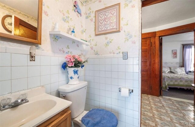 bathroom with vanity, toilet, and tile walls