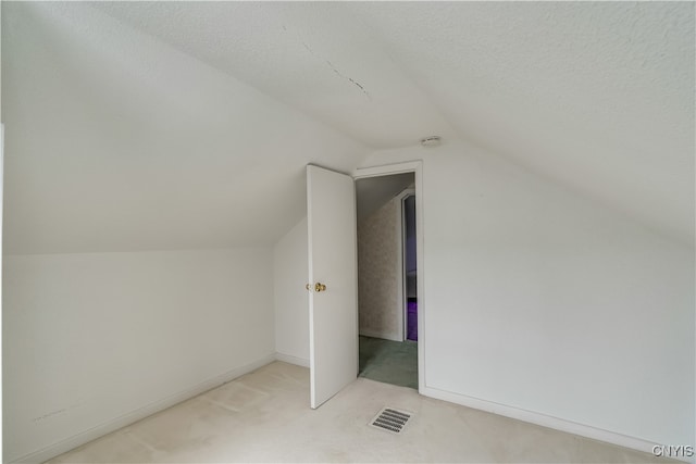 bonus room with vaulted ceiling, a textured ceiling, and light colored carpet