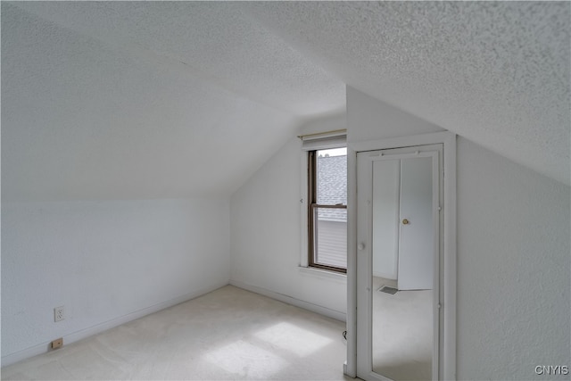 additional living space featuring lofted ceiling, light colored carpet, and a textured ceiling