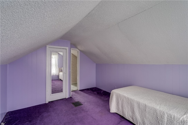 bedroom with vaulted ceiling, a textured ceiling, and carpet floors