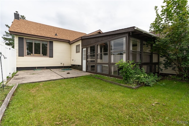 back of house featuring a lawn, a patio, and a sunroom