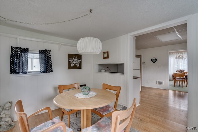 dining area with light wood-type flooring and an inviting chandelier