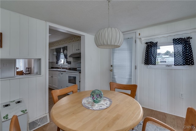 dining area with a textured ceiling, sink, and light wood-type flooring