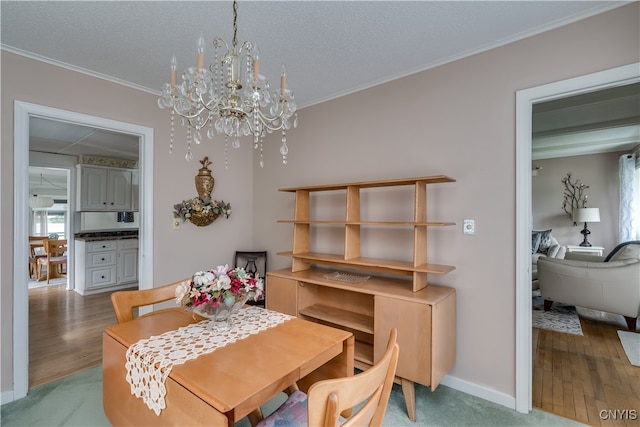 dining room with crown molding, a textured ceiling, hardwood / wood-style flooring, and a chandelier