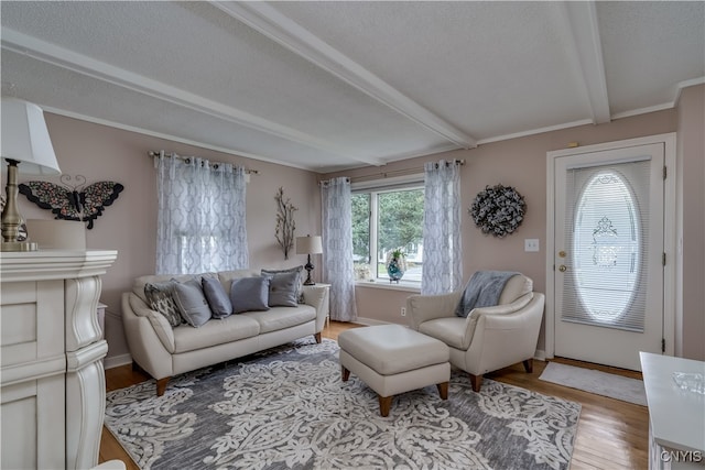 living room with a fireplace, crown molding, a textured ceiling, beam ceiling, and light hardwood / wood-style floors