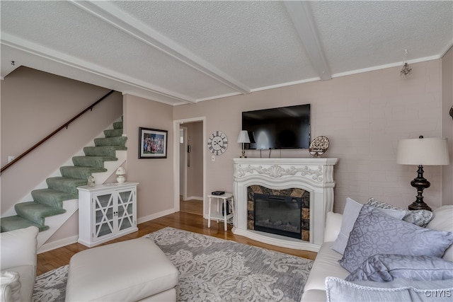 living room featuring a textured ceiling, a high end fireplace, beamed ceiling, and hardwood / wood-style flooring