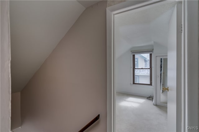 hallway featuring light carpet and lofted ceiling