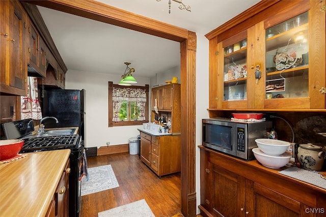 kitchen featuring black appliances, decorative light fixtures, and dark hardwood / wood-style flooring