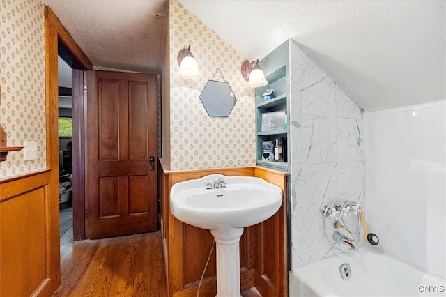 bathroom featuring a textured ceiling, vaulted ceiling, shower / tub combination, and hardwood / wood-style flooring