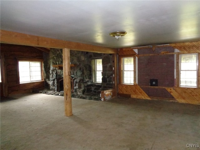 unfurnished living room with a large fireplace, plenty of natural light, and wooden walls