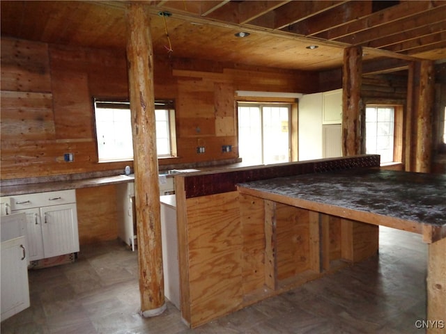 kitchen featuring white cabinetry, a wealth of natural light, and wooden walls