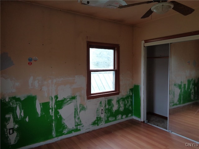 unfurnished bedroom featuring wood-type flooring, ceiling fan, and a closet