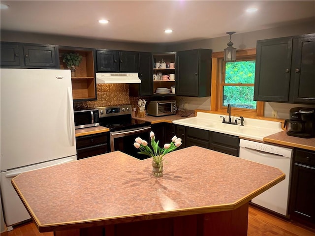 kitchen featuring light wood-type flooring, tasteful backsplash, stainless steel appliances, sink, and a kitchen island