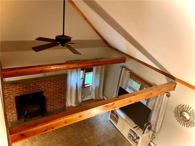 interior space featuring carpet, ceiling fan, a wood stove, and vaulted ceiling