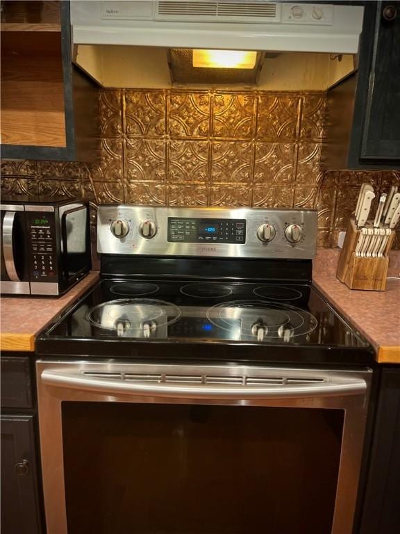 kitchen with appliances with stainless steel finishes, tasteful backsplash, and extractor fan