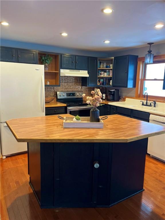 kitchen with white appliances, hardwood / wood-style flooring, blue cabinets, and sink