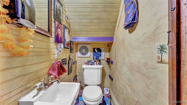 bathroom featuring sink, toilet, and wood walls