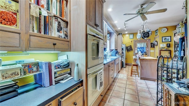 kitchen with ceiling fan, white oven, light tile patterned flooring, and rail lighting