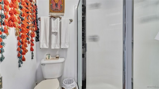 bathroom featuring a shower with shower door and toilet