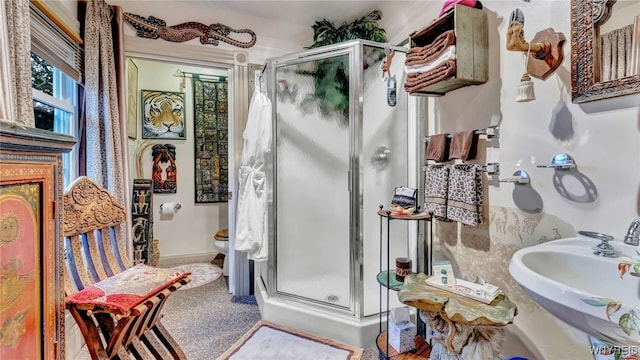 bathroom with a shower with shower door, sink, and toilet